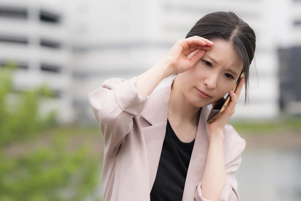 電話をしながら悩んでいる表情を浮かべる女性